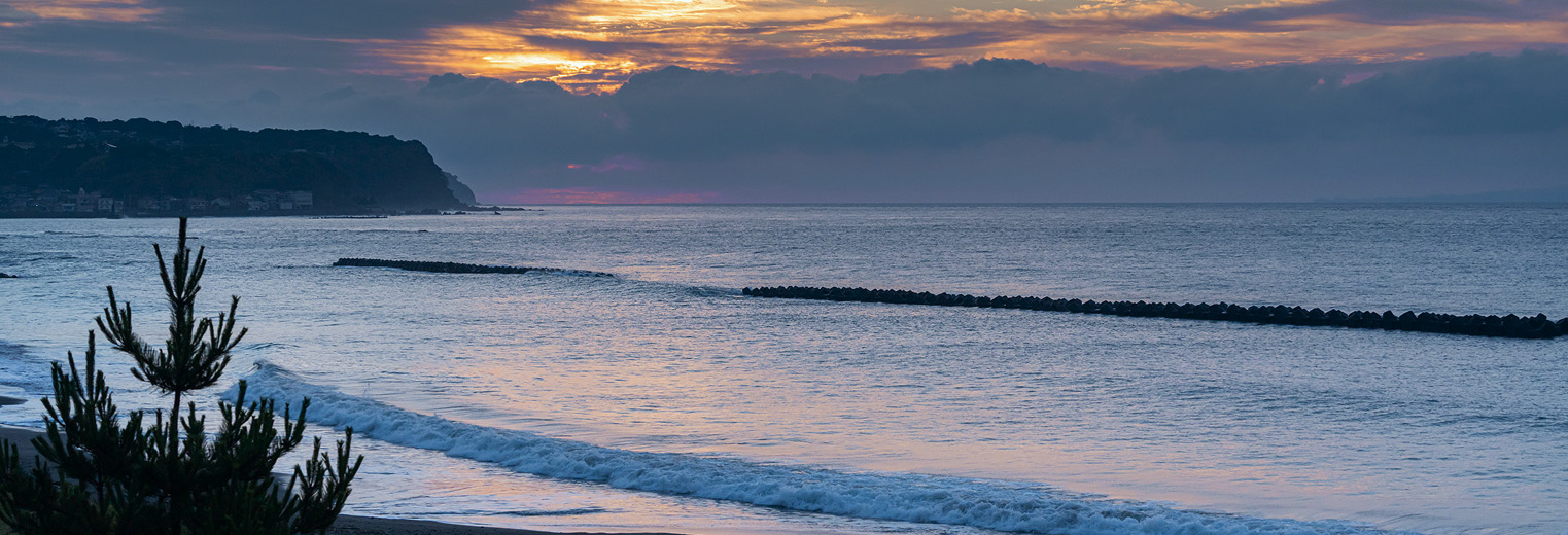 夕焼けに染まる海岸線と静かな波の風景