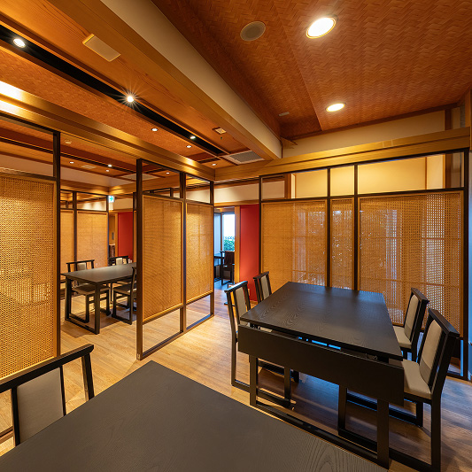 木製の床と天井、籐の仕切りで区切られた落ち着いた雰囲気の食事スペース。