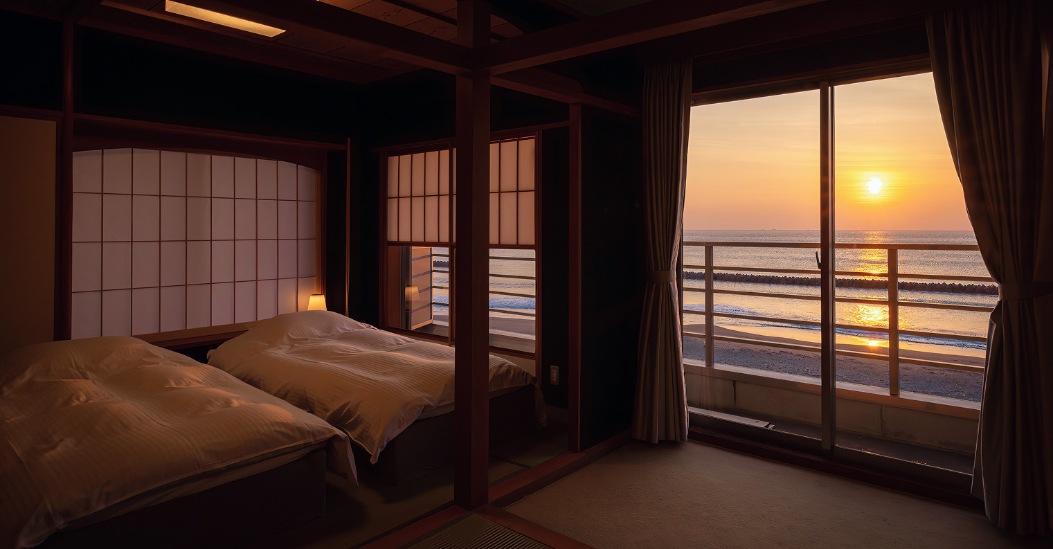 障子のしつらえが美しい和洋室。ベッド越しに大きな窓から海と夕日を望む、落ち着いた雰囲気の客室。