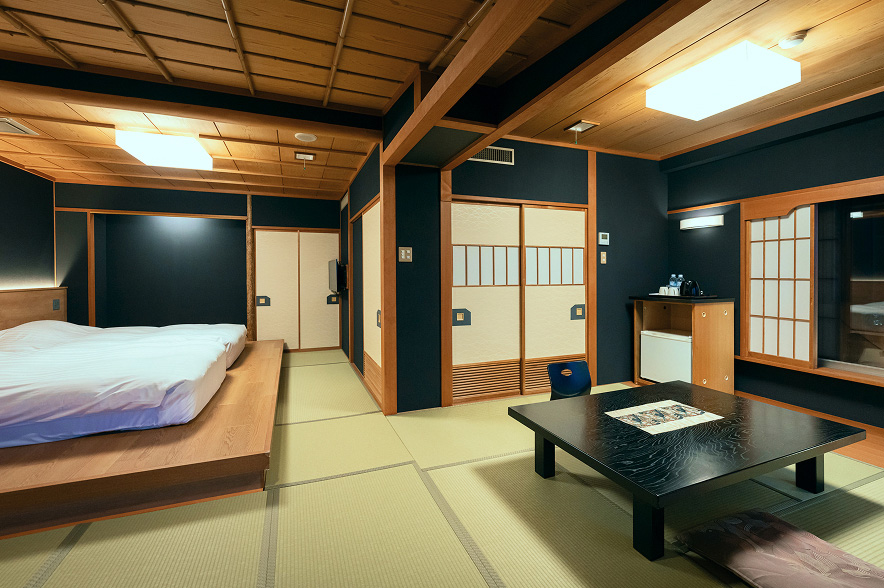 海を望む客室露天風呂。木製の格子に囲まれた湯船からは、穏やかな海と防波堤、遠くの水平線が見渡せます。