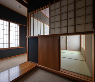 左手には、細やかな縦格子が連なる障子窓があり、外からの柔らかな光が室内に静かに広がっています。右手には繊細な木組みの縦格子が空間を緩やかに仕切っています。