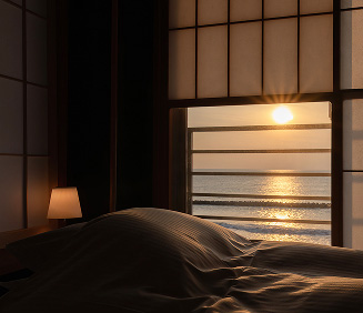 静かな朝を迎える寝室。窓の外には、水平線から昇ったばかりの朝日が、穏やかな海面を金色に照らしています。