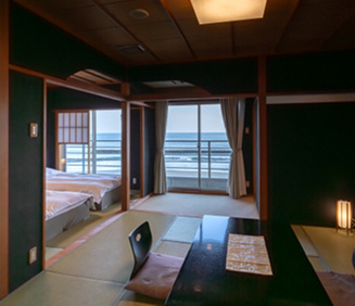 穏やかな昼下がりの光が差し込む、海辺の客室。手前には、光沢のある黒いテーブルがあり、中央に和柄のランチョンマットが置かれています。