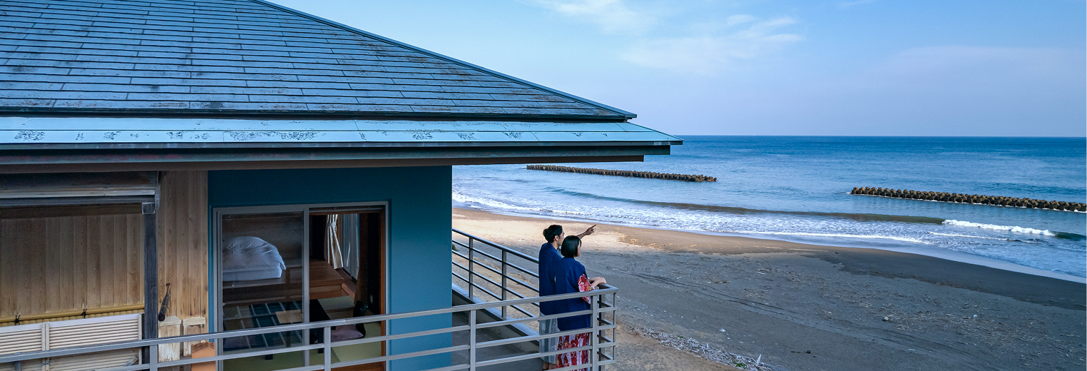 海辺の旅館のバルコニーから海を眺める浴衣姿のカップル